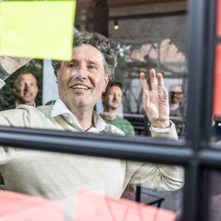 Een lachende deelnemer achter een raam vol post-its